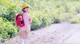 A woman in a pink shirt and yellow hat with a red backpack.