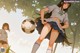 A girl in a school uniform kicking a soccer ball.