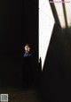 A woman standing in a dark room with a shadow on the wall.