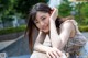 A young woman leaning against a wall with her hand on her chin.