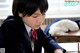 A woman in a school uniform writing on a piece of paper.