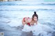 A woman in a red bikini laying in the ocean.