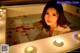 A woman sitting in a bathtub with candles in it.