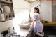 A woman in a maid outfit standing in a kitchen.