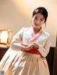 A woman in a white and orange hanbok posing for a picture.