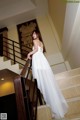 A woman in a white dress standing on a staircase.