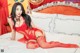 A woman in a red lingerie sitting on a bed.